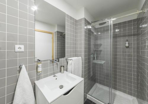 La salle de bains est pourvue d'un lavabo blanc et d'une douche. dans l'établissement Oporto Street Sá de Noronha, à Porto