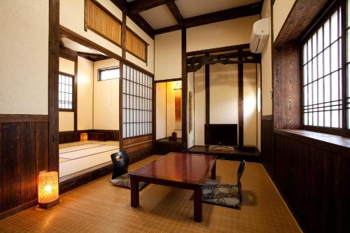 a room with a table and a bed with windows at Yunoyado Irifune in Aso