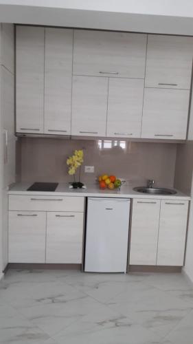 a white kitchen with white cabinets and a sink at Villa Orkidea in Sarandë