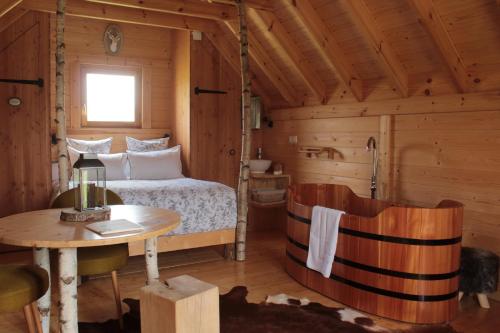 - une chambre dans une cabane en rondins avec un lit et une table dans l'établissement Shanti Lac Cabanes gîtes insolites et espace bien-être Bordeaux, à Berson