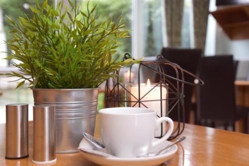 a cup of coffee on a table with a potted plant at Palazzo Hotel - direkt im Zentrum in Mönchengladbach