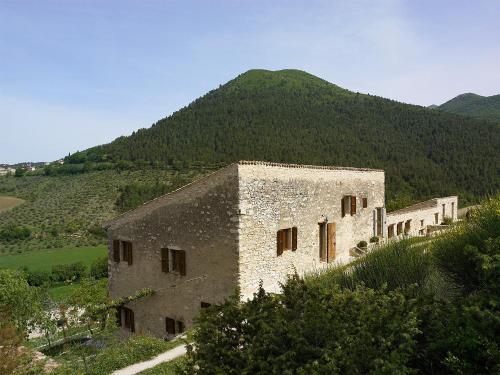 an old stone building with a mountain in the background at Borgo di Pianciano in Spoleto