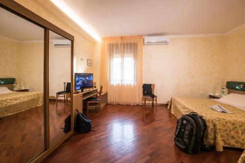 a room with two beds and a desk with a computer at Hotel Vega Perugia in Perugia