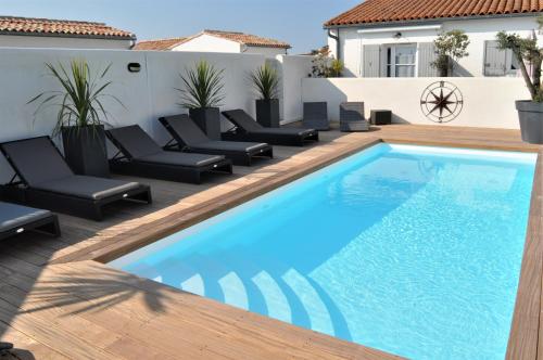 a swimming pool on a deck next to a house at Fleur de Ré in Loix