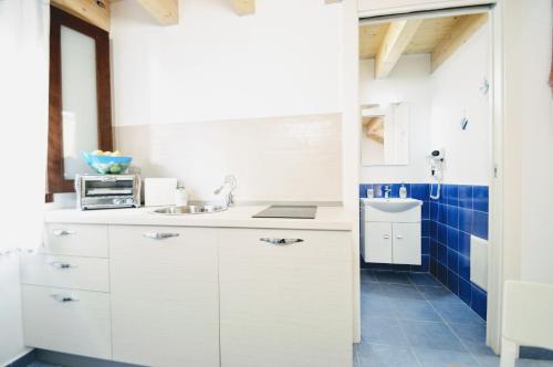 a kitchen with white cabinets and blue tiles at Sciabika Home - Edificio Eolie in Castellammare del Golfo