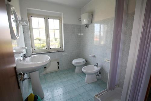 a bathroom with a sink and a toilet and a window at Appartamento Terry - Casa vacanze in Capo Vaticano