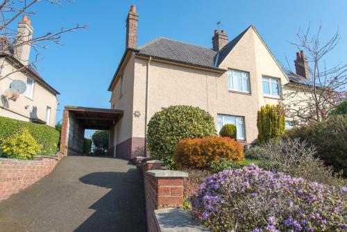 a house with a driveway and flowers in front of it at Park Road Holiday Home - Spacious 3 bedroom house with garden near Edinburgh in Rosyth