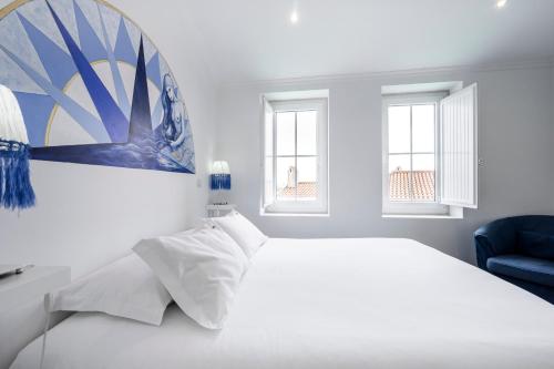 ein weißes Schlafzimmer mit einem Bett und einem blauen Stuhl in der Unterkunft Castle Inn Lisbon Apartments in Lissabon