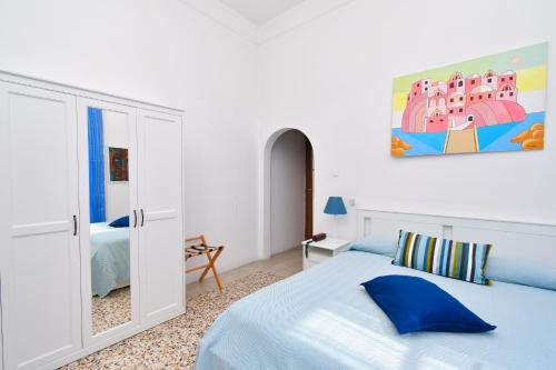 biała sypialnia z niebieskim łóżkiem i lustrem w obiekcie Villa Panoramica - Ischia Ponte w mieście Ischia