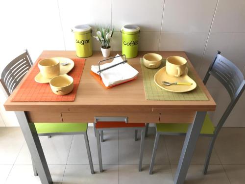 una mesa de madera con tazas y platillos. en APARTARMENTOS A D´MARIA, en Sanxenxo