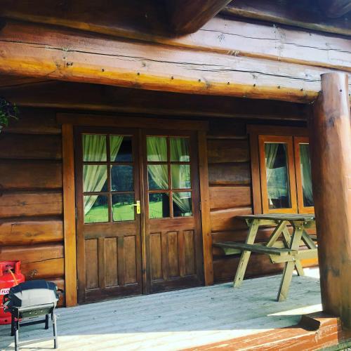 a cabin with wooden doors and a picnic table on the porch at Log home village in Ulverston