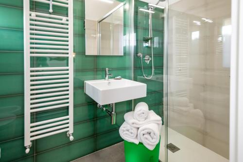 bagno con pareti verdi piastrellate e lavandino di Umémà B&B ad Albenga