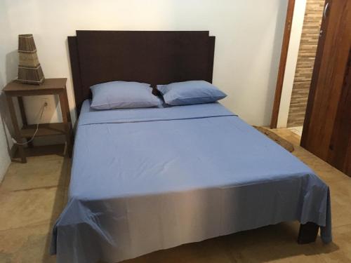 Cama en habitación con colcha y almohadas azules en Os Navegantes A en Guajiru