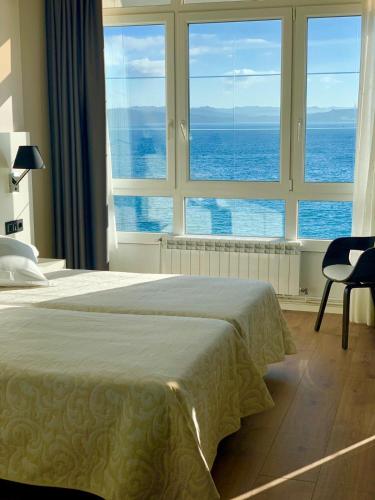 a bedroom with a bed with a view of the ocean at Hotel La Cruz in Muxia
