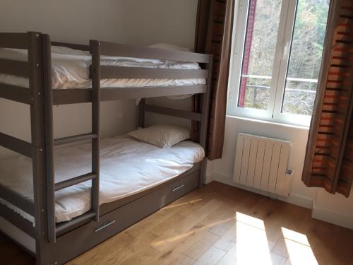 a bedroom with bunk beds in a room with a window at Magnifique et lumineux appartement au cœur du Sancy in Saint-Nectaire