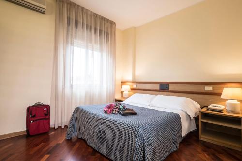 a hotel room with a bed and a red suitcase at Hotel Vega Perugia in Perugia