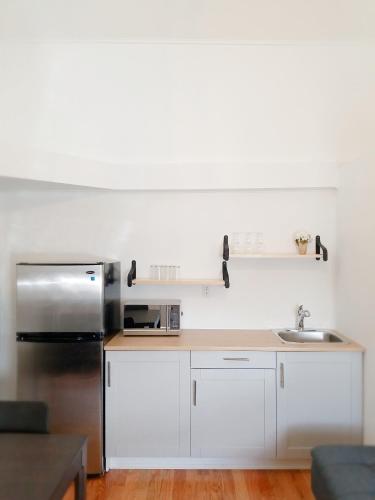 a kitchen with white cabinets and a stainless steel refrigerator at Rothesay Motel in Rothesay