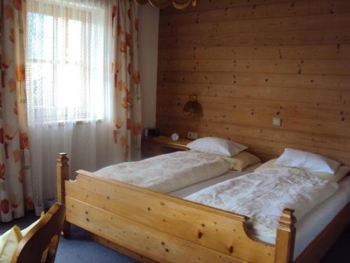 two beds in a bedroom with a wooden wall at Haus Postfeld in Alpbach