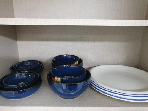 four blue bowls and plates sitting on a shelf at DAGA59 Guesthouse in Daejeon