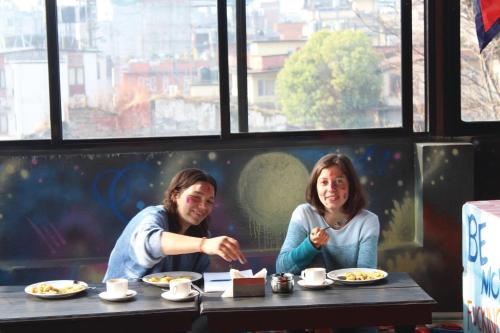 two women sitting at a table eating food at Rest Up Kathmandu Hostel in Kathmandu