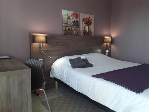 een slaapkamer met een bed en een bureau met 2 lampen bij Relais Motel de Maisonnay in Maisonnay
