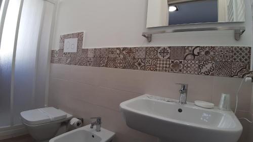 a white bathroom with a sink and a toilet at Le Due Sicilie B&B in Lascari