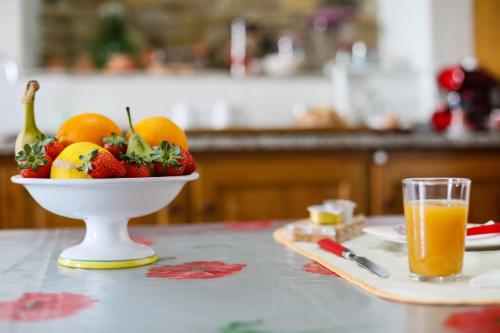 a bowl of fruit on a table with a glass of orange juice at St. Michele b&b in Patti