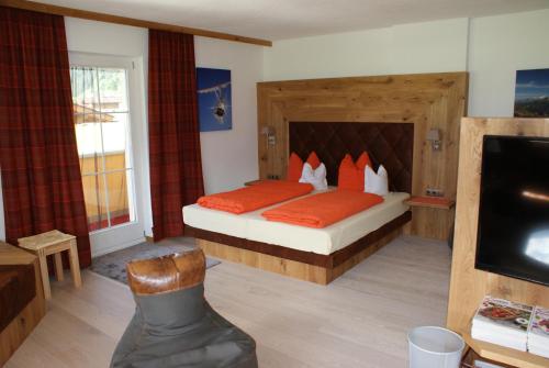 1 dormitorio con 1 cama con almohadas de color naranja y TV en Traum-Ferienwohnungen Wechselberger Schwendau en Schwendau