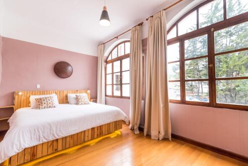 1 dormitorio con 1 cama grande y ventanas grandes en Viajero Quito Hostel, en Quito