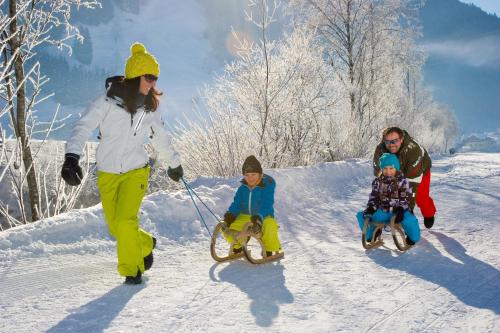 a woman and two children riding on skis in the snow at Hotel-Pension Egger in Grossarl