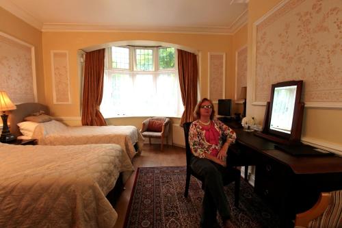 a woman sitting at a desk in a hotel room at Acorn Guest House in Hull in Hull