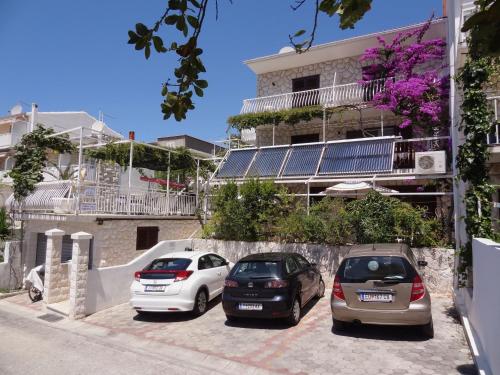 three cars parked in a parking lot in front of a building at Balic Apartments - ZF Hvar in Hvar