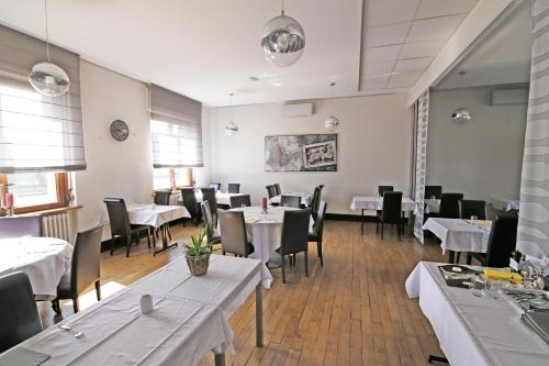 a dining room with tables and chairs and white tables and chairsktop at Hôtel Restaurant Au Coucou in Pulversheim