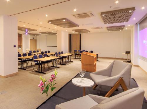 a conference room with tables and chairs and a projection screen at Mercure Santa Marta Emile in Santa Marta