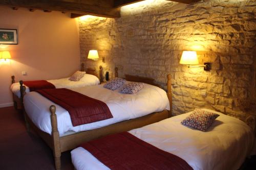 a bedroom with two beds and a stone wall at La Fleur de Lys in Cormatin