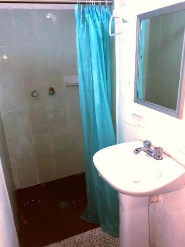 a bathroom with a sink and a shower with a blue shower curtain at Casa Lao Centro in Zihuatanejo