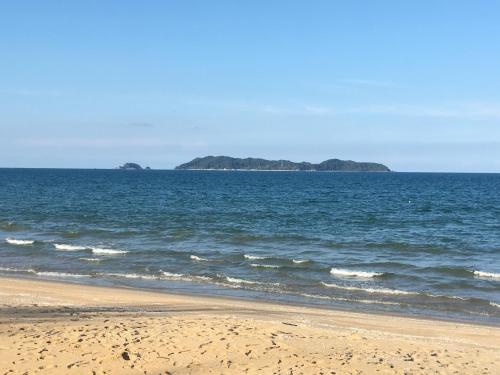 an empty beach with an island in the ocean at Zara Homestay in Marang