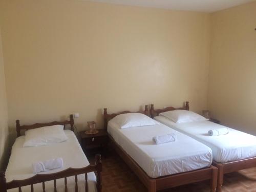 two beds in a room with white sheets and pillows at Sissi's B&B in Ponta do Sol