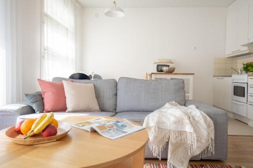 Una sala de estar con un sofá y una mesa con fruta. en Torget Apartment Länsiportti, en Pori