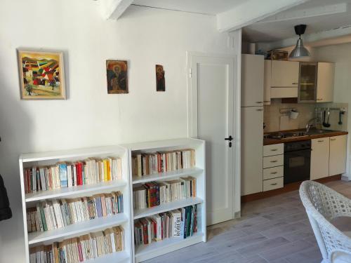 a kitchen with two white book shelves filled with books at Au coeur de Tende in Tende