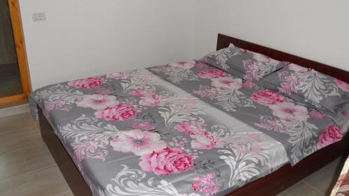 a bed with pink and gray sheets and pink flowers at Vilele Brise de Mer in 2 Mai