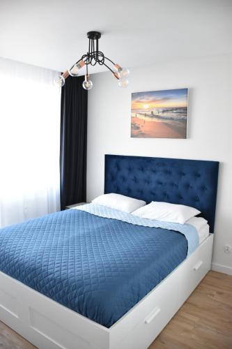 sypialnia z niebieskim łóżkiem z niebieskim zagłówkiem w obiekcie Apartamenty Balticum - Bliżej Morza z garażem w Kołobrzegu
