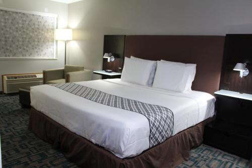 Una habitación de hotel con una cama grande y una silla. en Westbridge Inn & Suites, en Carrollton