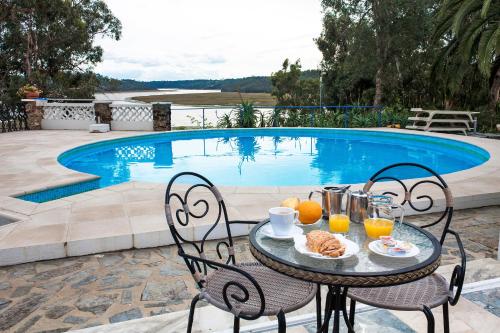a table with food on it next to a swimming pool at Moinho Da Asneira - Duna Parque Resorts & Hotels in Vila Nova de Milfontes