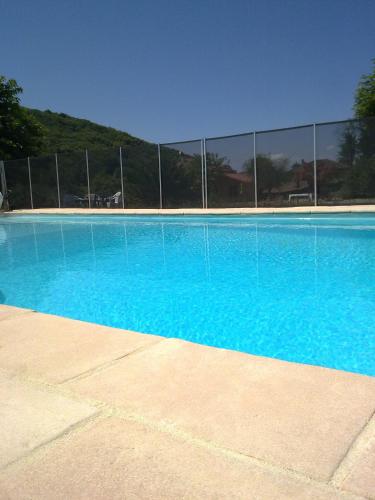 une piscine bleue avec une clôture en arrière-plan dans l'établissement Gites de La Croisée des Chemins - Piscine Chauffée - Spa, Hammam et Sauna, à Izeaux