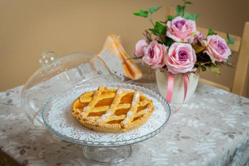 a pie on a table with a vase of roses at Agriturismo Country Casale Rufo in Sonnino