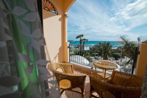 a balcony with chairs and a table and the ocean at Hotel Stella Maris in Villasimius