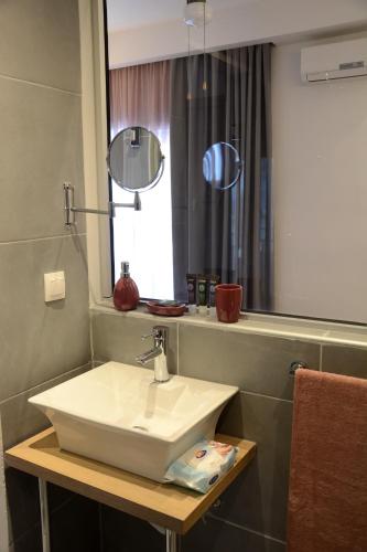 a bathroom with a white sink and a mirror at Ammos Hotel in Agia Triada