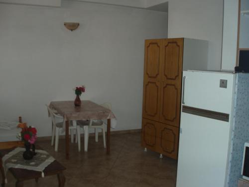a kitchen with a table and a white refrigerator at Hellen Studios in Megali Ammos