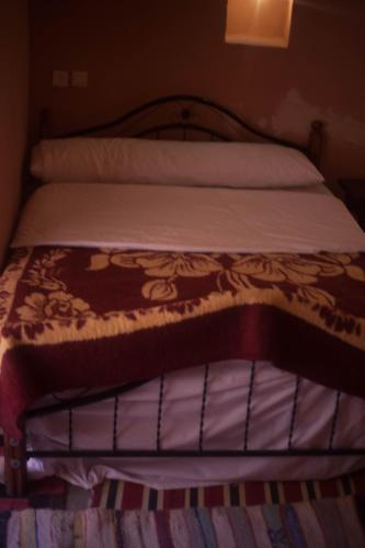 a bed with a brown and white blanket on it at Kasbah Ait Kassi in Boumalne